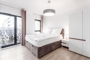 a white bedroom with a bed and a large window at Rent like home - Dwie Motławy III z parkingiem in Gdańsk