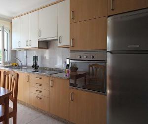 eine Küche mit einem Kühlschrank aus Edelstahl und Holzschränken in der Unterkunft Apartamento Playa de Louro in Louro