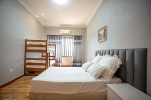 um quarto com uma cama com lençóis brancos e almofadas em Ponta d’ ouro lia’s house em Ponta do Ouro