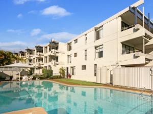 un edificio con piscina frente a un edificio en Warroo Apartments en Alexandra Headland