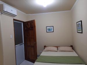 a small bedroom with a bed and a door at Alimpay Foresters Apartment in Panglao