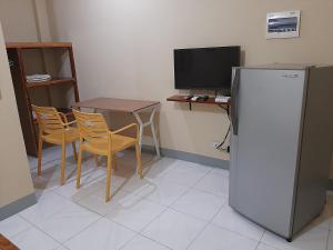 a kitchen with a table and a refrigerator and a television at Alimpay Foresters Apartment in Panglao
