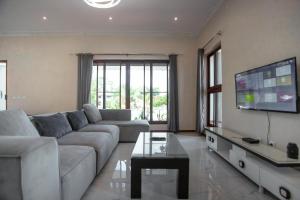 sala de estar con sofá y TV de pantalla plana en Ponta d’ ouro lia’s house, en Ponta do Ouro