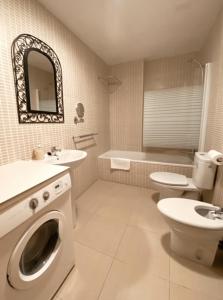 bagno con lavandino e servizi igienici e lavatrice. di Apartamentos Laurel a Logroño