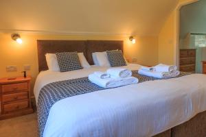 a bedroom with a large bed with towels on it at Bumble Bee Cottage in Burley