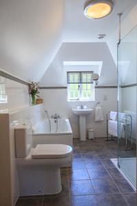 a bathroom with a tub and a toilet and a sink at Bumble Bee Cottage in Burley