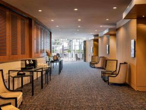 a hallway with tables and chairs in a building at Novotel Auckland Ellerslie in Auckland