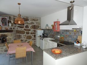 cocina con mesa, sillas y pared de piedra en A CASA COM 2 PEREIRAS en Terras de Bouro