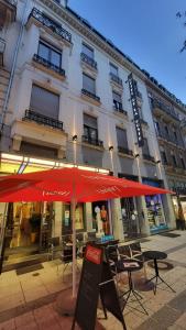 a building with a red umbrella in front of it at HOTEL de la POSTE in Esch-sur-Alzette