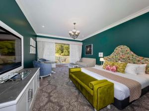 a bedroom with a king sized bed and a television at Grand Mercure Basildene Manor in Margaret River Town