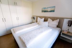 a bedroom with a large white bed with white cabinets at Panorama_Apartment 1 P6 optional P in Plau am See