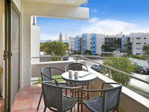 a balcony with a table and chairs and a view of a city at Warroo Apartments in Alexandra Headland