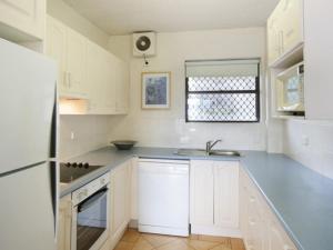 Biała kuchnia ze zlewem i lodówką w obiekcie Warroo Apartments w mieście Alexandra Headland