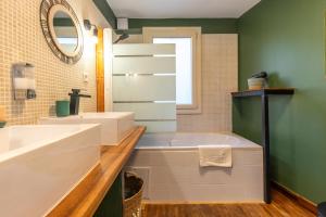 La salle de bains est pourvue d'une baignoire, d'un lavabo et d'un miroir. dans l'établissement « La Grrr'Authentique » - Maison Troglodyte Unique, à Amboise