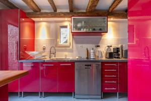 a kitchen with red cabinets and a sink at « La Grrr'Authentique » - Maison Troglodyte Unique in Amboise