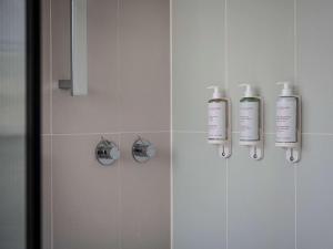 een douche met twee shampooflessen aan de muur bij Elkonin Tel Aviv - MGallery Hotel Collection in Tel Aviv