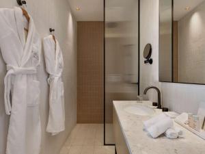 een witte badkamer met een wastafel en een douche bij Elkonin Tel Aviv - MGallery Hotel Collection in Tel Aviv
