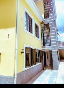 une maison jaune avec des fenêtres donnant sur une rue dans l'établissement Select Elegant 3 Rooms 3 sized king-bed @ Abuja FCT, à Abuja