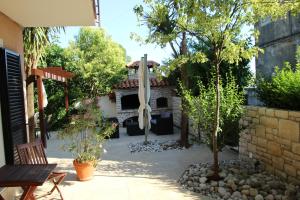 a patio with a stone fireplace and a tree at Apartments Eva in Umag