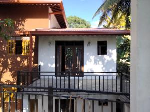 a house with a balcony in front of it at Rose Cottage in Digana
