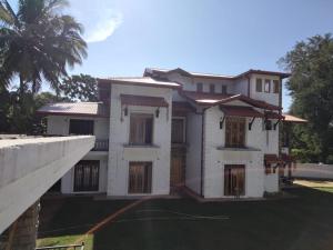 a large white house with a palm tree at Rose Cottage in Digana