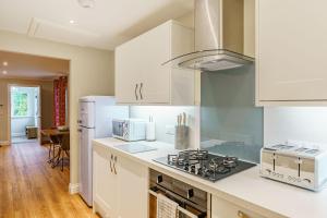 a kitchen with white cabinets and a stove top oven at Peregrine Cottage with Hot Tub in Newton Stewart