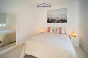 een witte slaapkamer met een bed en 2 lampen bij Vivienda Magallanes in Sanlúcar de Barrameda +27 foto's