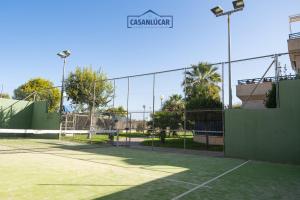 een tennisbaan met een hek en een tennisbaan bij Vivienda Magallanes in Sanlúcar de Barrameda