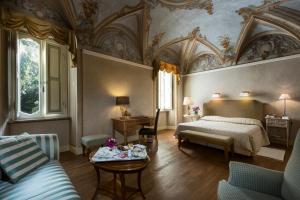 a bedroom with a bed and a couch and a table at Posta Donini 1579 - UNA Esperienze in San Martino in Campo