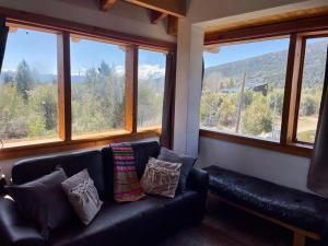 a living room with a black couch and windows at Casa luminosa entre montañas in San Carlos de Bariloche