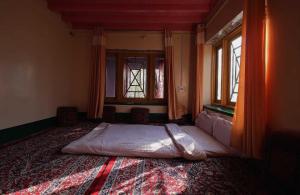 a bed in a room with two windows at OYO Flagship 4945 AR LODGE in Srinagar