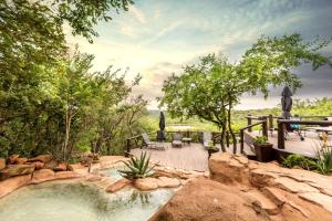 a hot tub in a backyard with a patio and trees at Elephant Rock Private Safari Lodge in Ladysmith