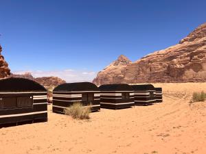 uma fila de cabanas negras no deserto em Bedouin Tribe Camp Wadi Rum em Wadi Rum