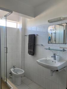 uma casa de banho branca com um lavatório e um WC em La Péninsule - Town Apartment No. 3 em Curepipe