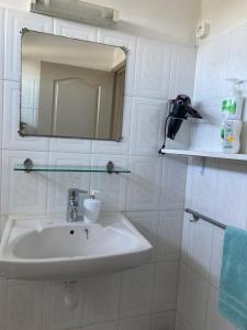 uma casa de banho branca com um lavatório e um espelho em La Péninsule - Town Apartment No. 3 em Curepipe