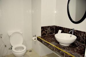 a bathroom with a white toilet and a sink at Isla De Oro Hotel in Mamburao