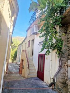 an alley with stairs and a building with a red door at petite maison de village calme in Rodès