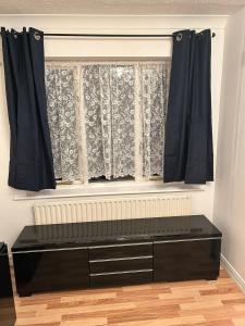 a black dresser in front of a window at Kelvin Gardens in Croydon