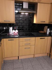 a kitchen with wooden cabinets and a stove top oven at Kelvin Gardens in Croydon