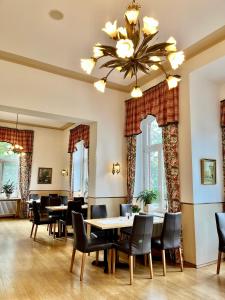 une salle à manger avec des tables et des chaises ainsi qu'un lustre dans l'établissement Villa Sophienhöhe, à Kerpen