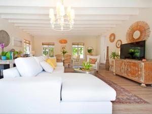 uma sala de estar com um sofá branco e uma televisão em That Cape Town House em Dagbreek