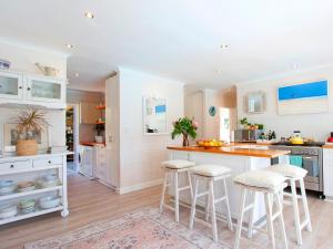 Una cocina con gabinetes blancos y taburetes de bar. en That Cape Town House, en Dagbreek