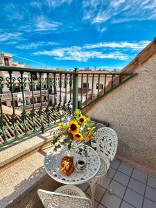 una mesa con un jarrón de girasoles en el balcón en Hotel Reyesol en Fuengirola