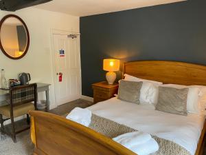 a bedroom with a bed and a desk and a mirror at The Bathurst Arms in Cirencester