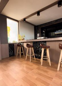 a bar with three wooden stools in a room at Clarks Exotica, Kamadhoo Maldives in Baa Atoll