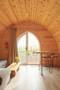 Woodmancote的住宿－Foot of the Downs Shepherds Hut，客房设有木制天花板、桌子和窗户。