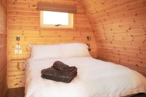 Una cama en una cabaña de madera con una toalla. en Foot of the Downs Shepherds Hut en Woodmancote