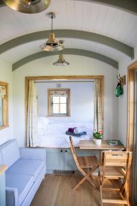 Woodmancote的住宿－Foot of the Downs Shepherds Hut，一间卧室配有一张床、一张桌子和一张桌子