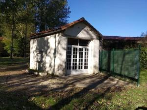 ein kleines weißes Gebäude mit einem Tor im Gras in der Unterkunft Cottage chaleureux au calme in Salles-de-Barbezieux
