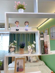 un estante con muñecas y macetas. en PTJ Style Condotel คอนโดเมืองทอง P2 en Nonthaburi